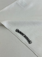 White shirt hem detail with small black logo patch