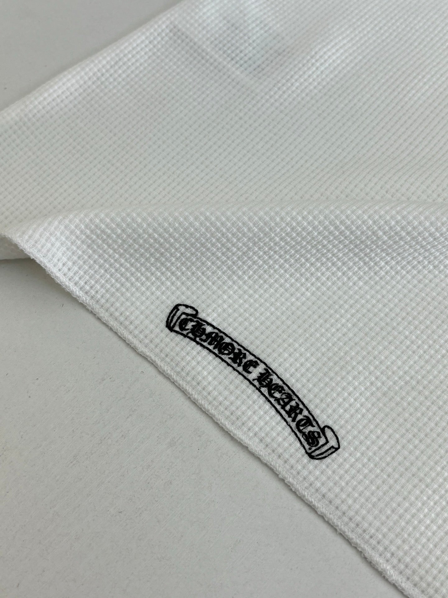 White shirt hem detail with small black logo patch