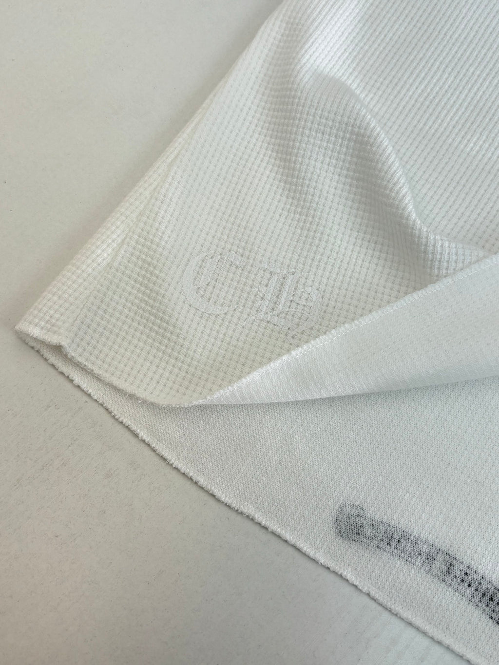 White long-sleeve shirt hem and sleeve seam with subtle ribbed texture