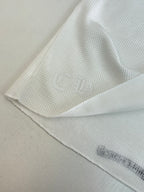 White long-sleeve shirt hem and sleeve seam with subtle ribbed texture
