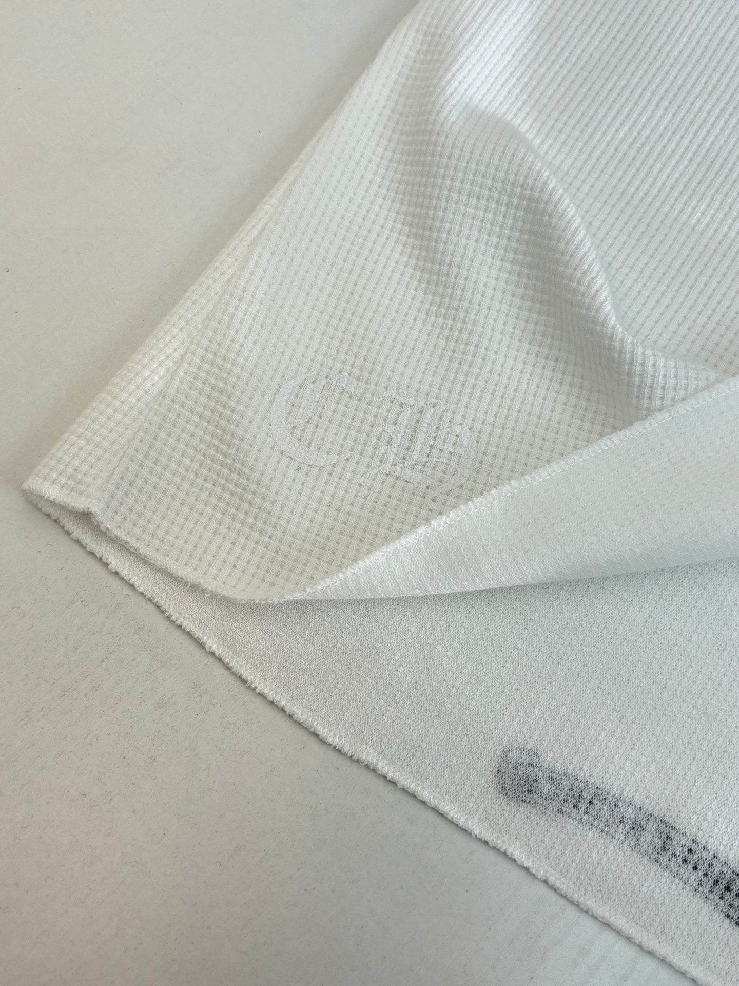 White long-sleeve shirt hem and sleeve seam with subtle ribbed texture