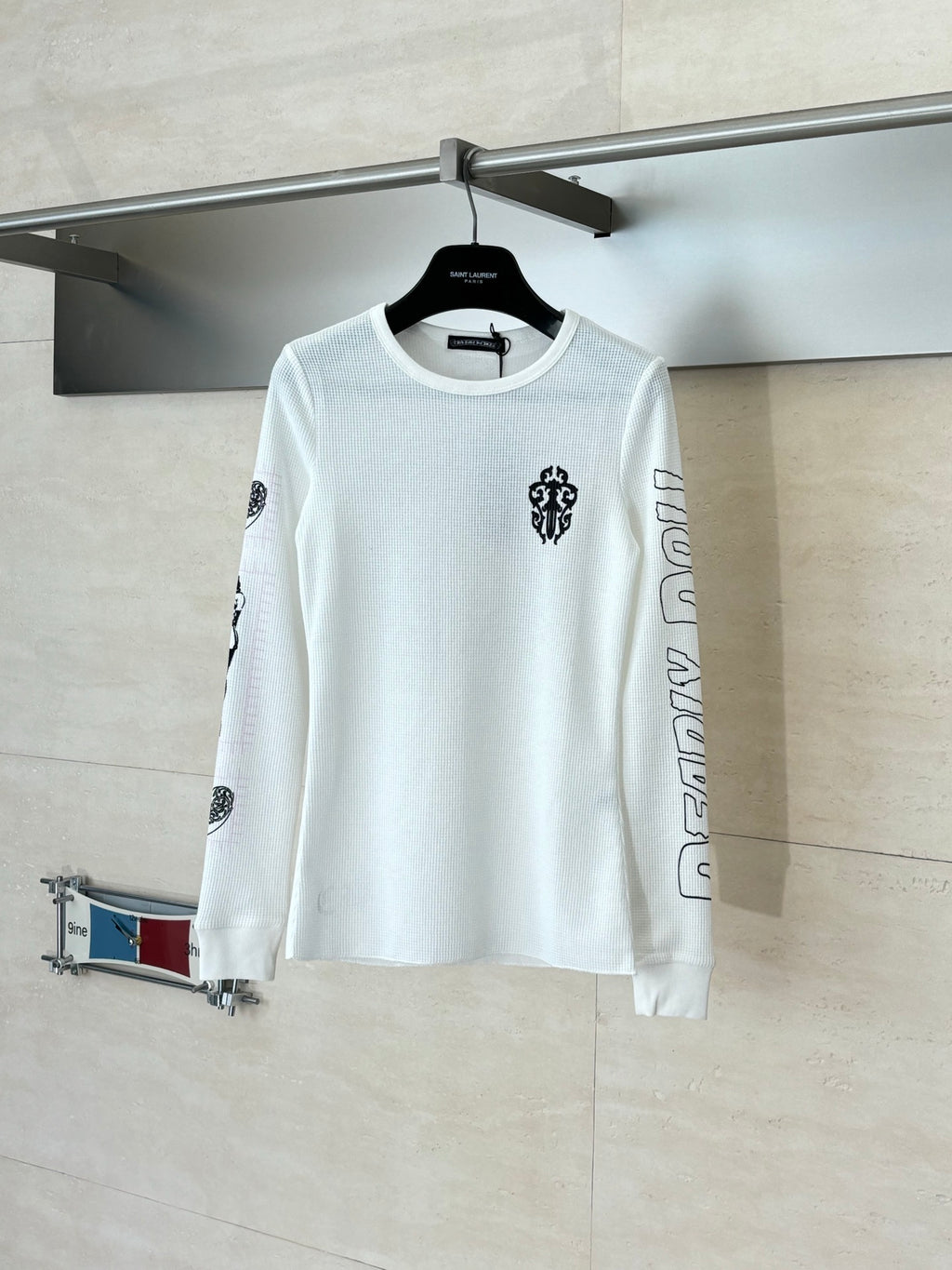 White long-sleeve crewneck shirt with small chest emblem and sleeve prints