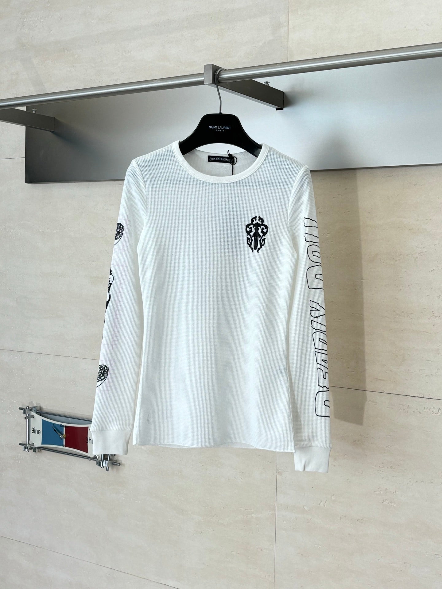 White long-sleeve crewneck shirt with small chest emblem and sleeve prints