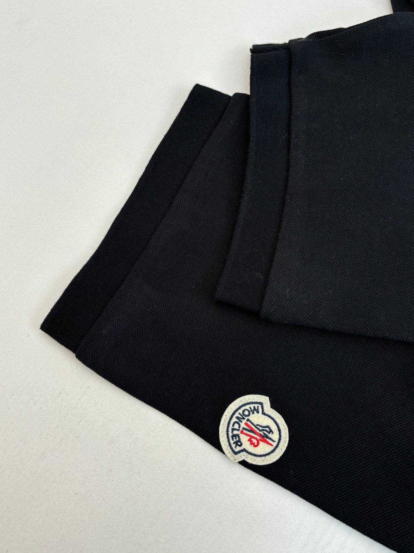 Moncler polo shirt side view, dark navy with small circular logo patch