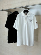 White Moncler polo shirt with M logo on hanger, paired with black polo behind