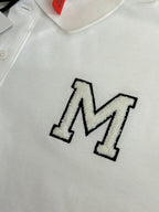 Close-up of white polo shirt with embroidered M logo on chest