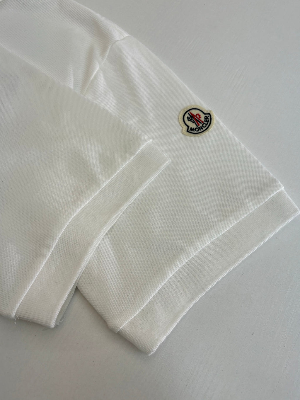 White Moncler polo sleeve patch with small Moncler logo