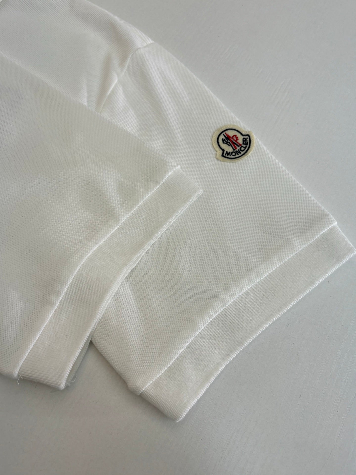 White Moncler polo sleeve patch with small Moncler logo