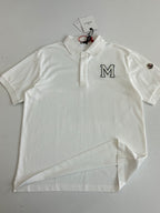 White Moncler polo shirt flat lay with M logo, collar buttons, sleeve studs