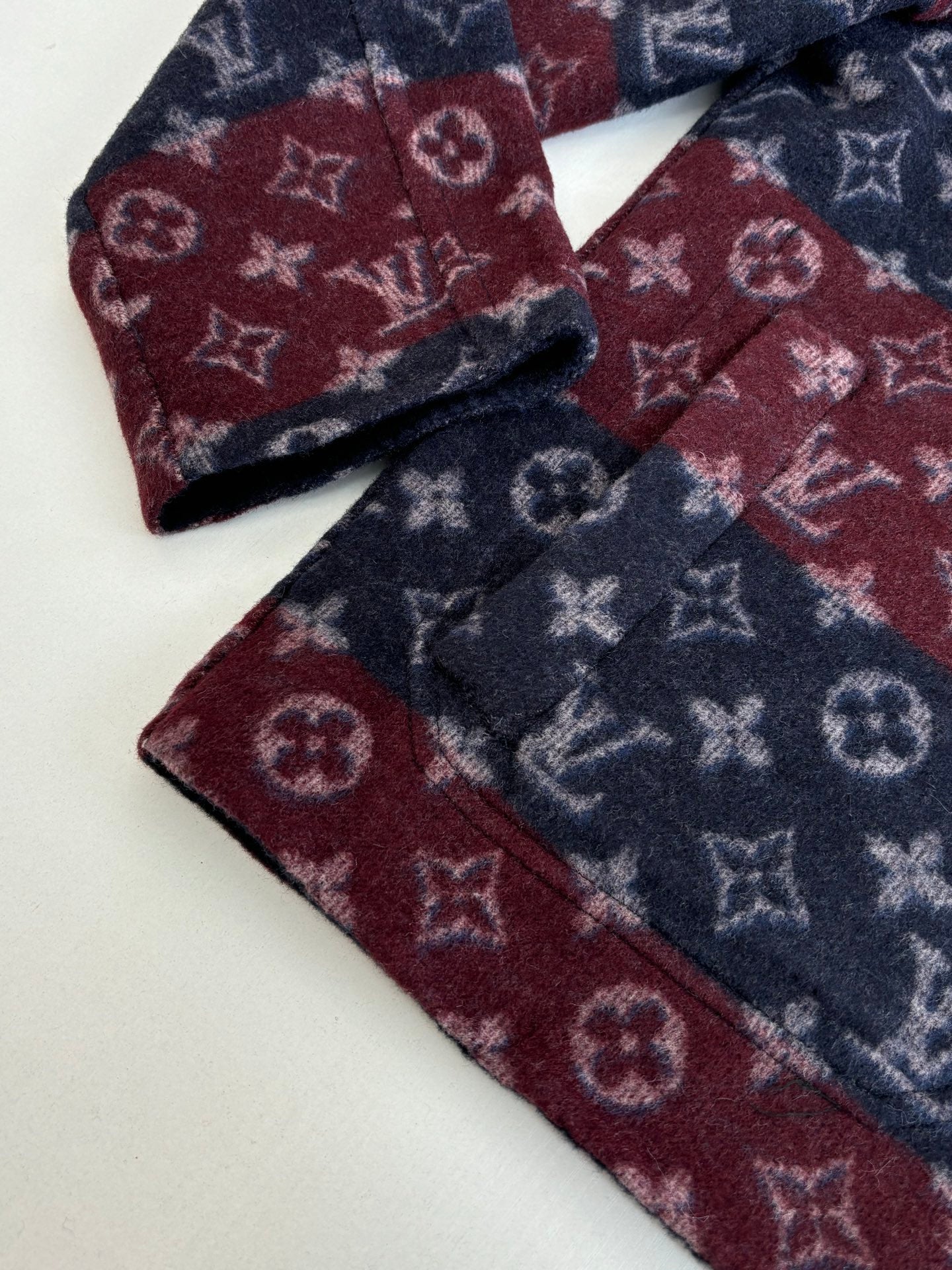 Maroon and navy monogram knit fabric detail with folded seams.