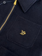 Dark navy Louis Vuitton jacket chest pocket with gold LV logo and gold zipper.