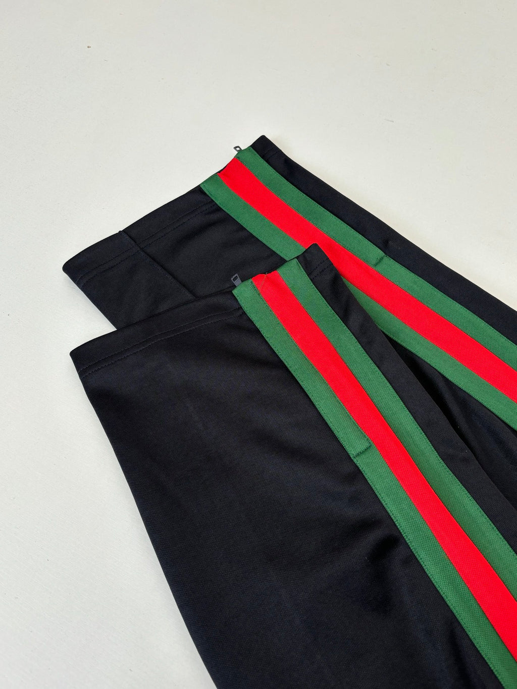 Black track pants with green and red diagonal stripe accents
