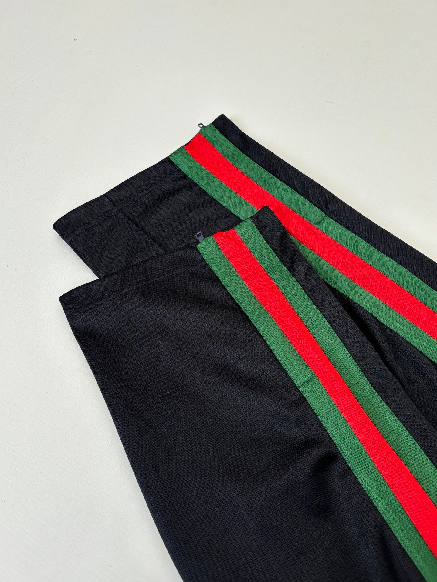 Black track pants with green and red diagonal stripe accents