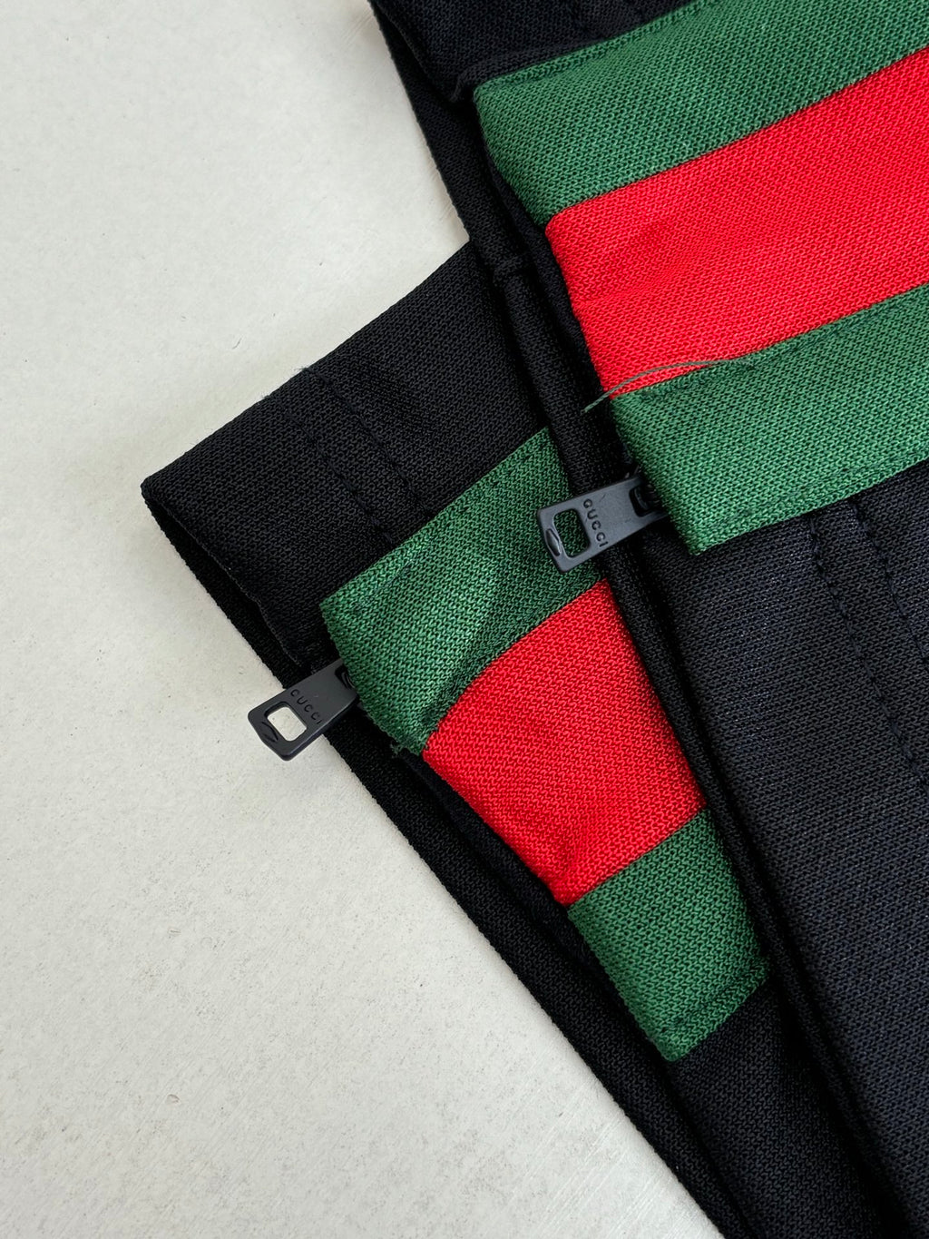 Navy pants detail with green-red stripe trim and black buckle strap