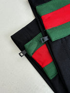 Navy pants detail with green-red stripe trim and black buckle strap