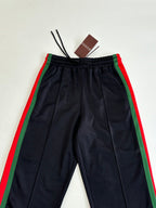 Navy track pants with elastic waistband and green-and-red side stripe