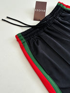 Navy track pants with elastic drawstring waistband and green-red side stripe