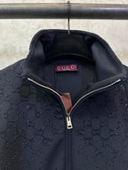 Dark Gucci monogram zip-up jacket showing Gucci label and metal zipper pull