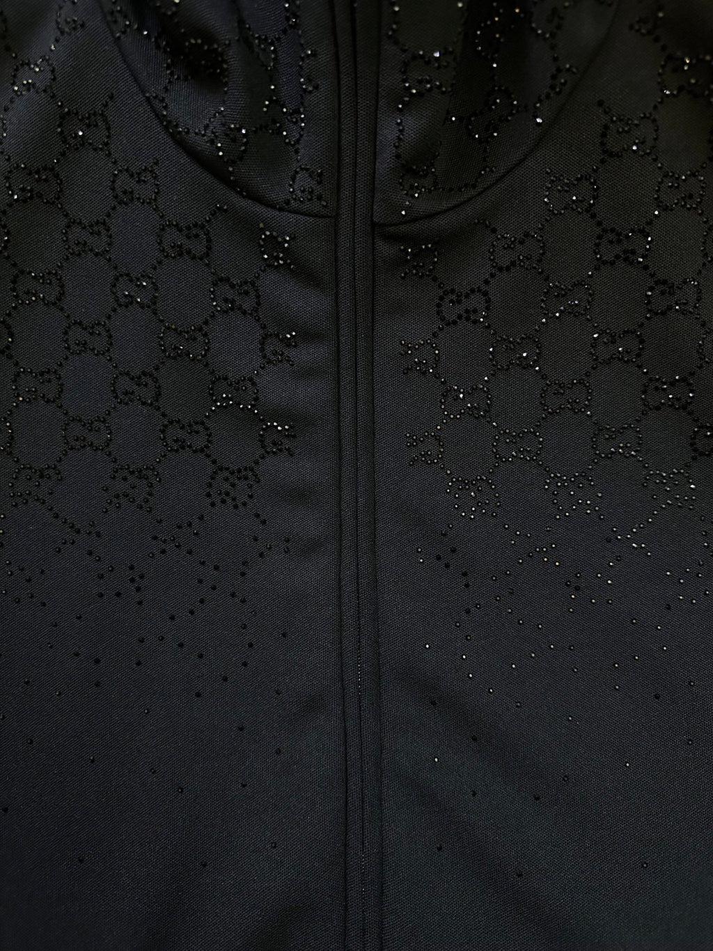 Dark Gucci monogram zip-up jacket fabric detail with stitched zipper front