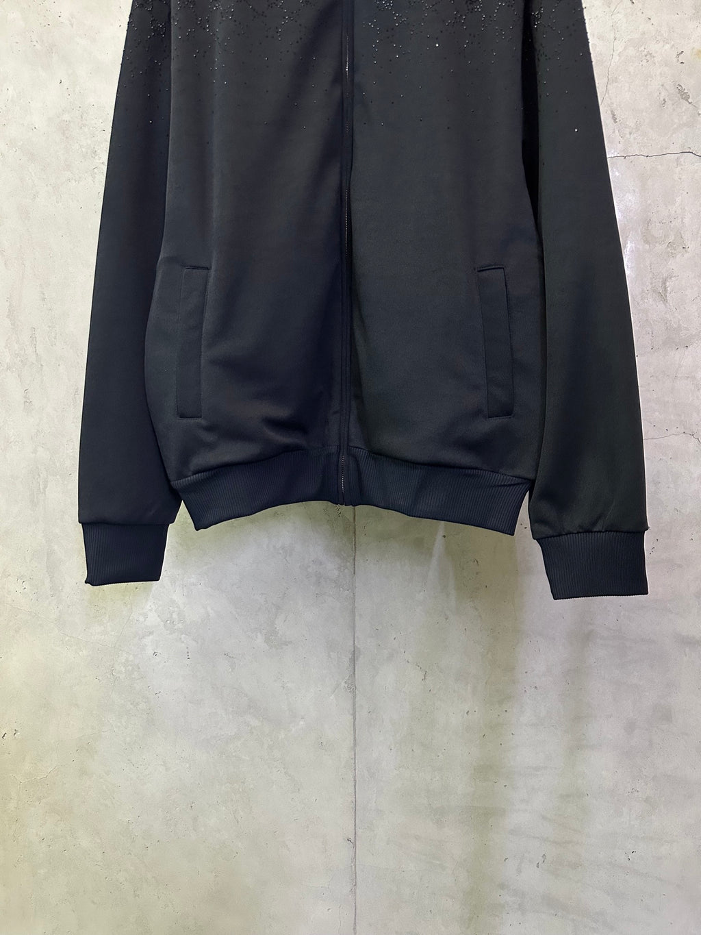Dark Gucci zip-up jacket front with logo pattern, zip and flap pockets