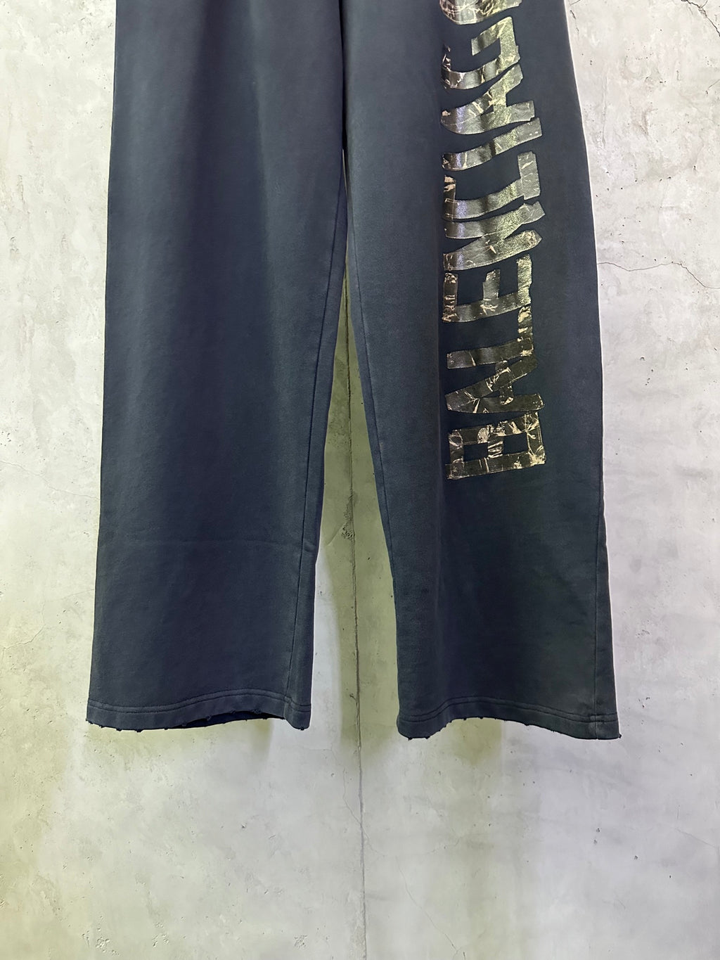 Close-up of dark blue pants leg with vertical gold-toned graphic detailing