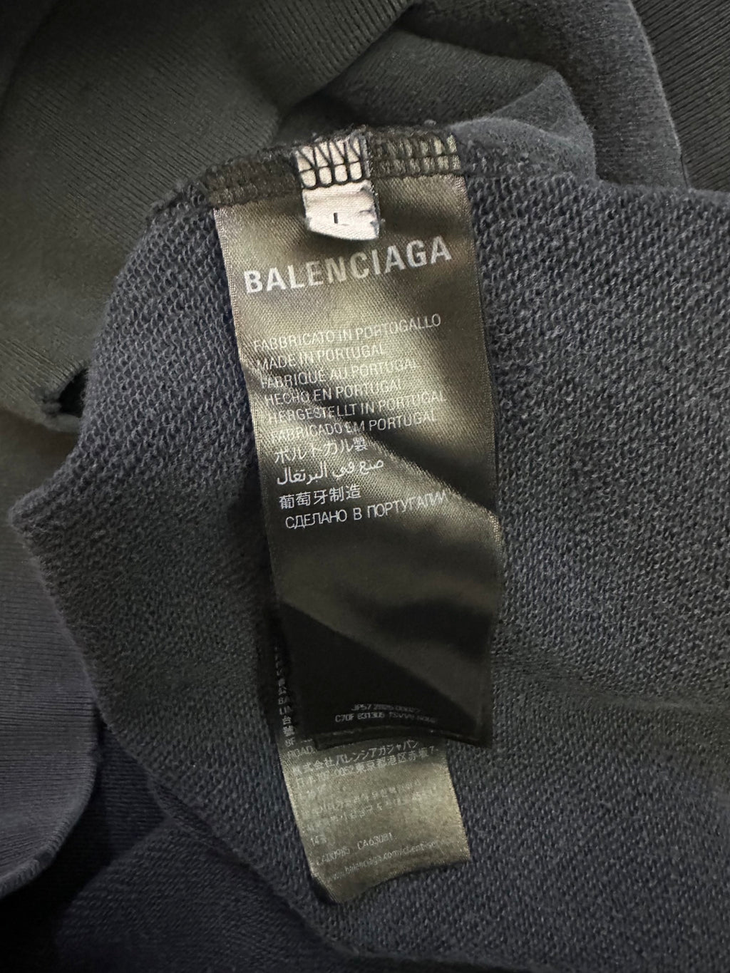 Balenciaga hoodie neck label and care tag inside collar on dark gray fabric