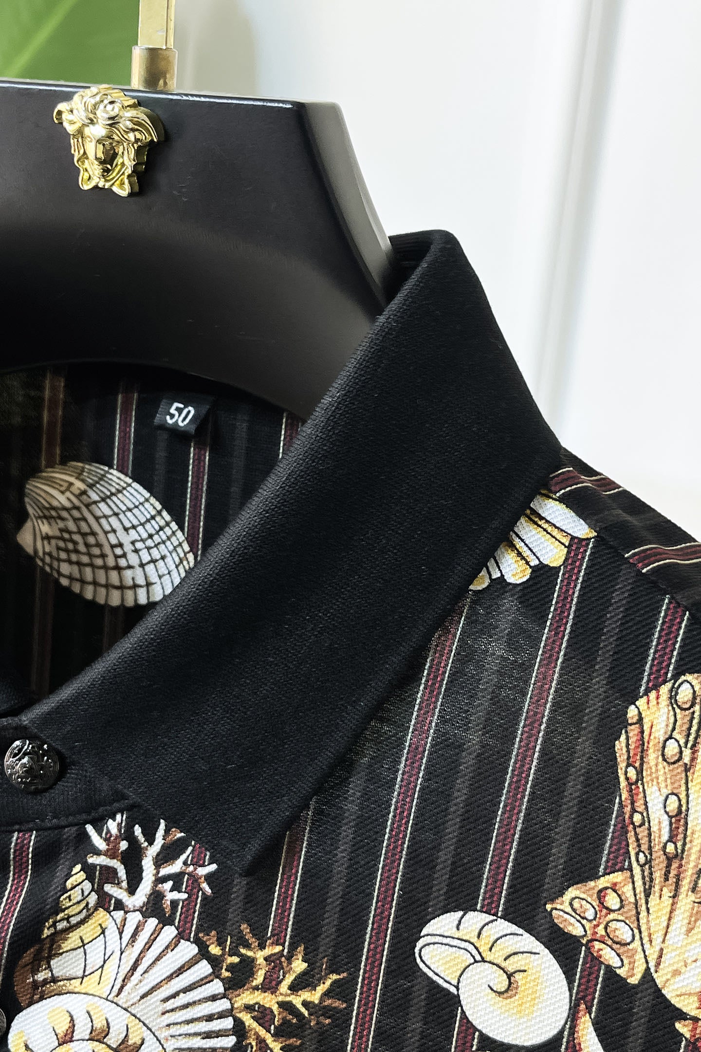 Black button-up shirt sleeve close-up with textured fabric and seashell graphic print