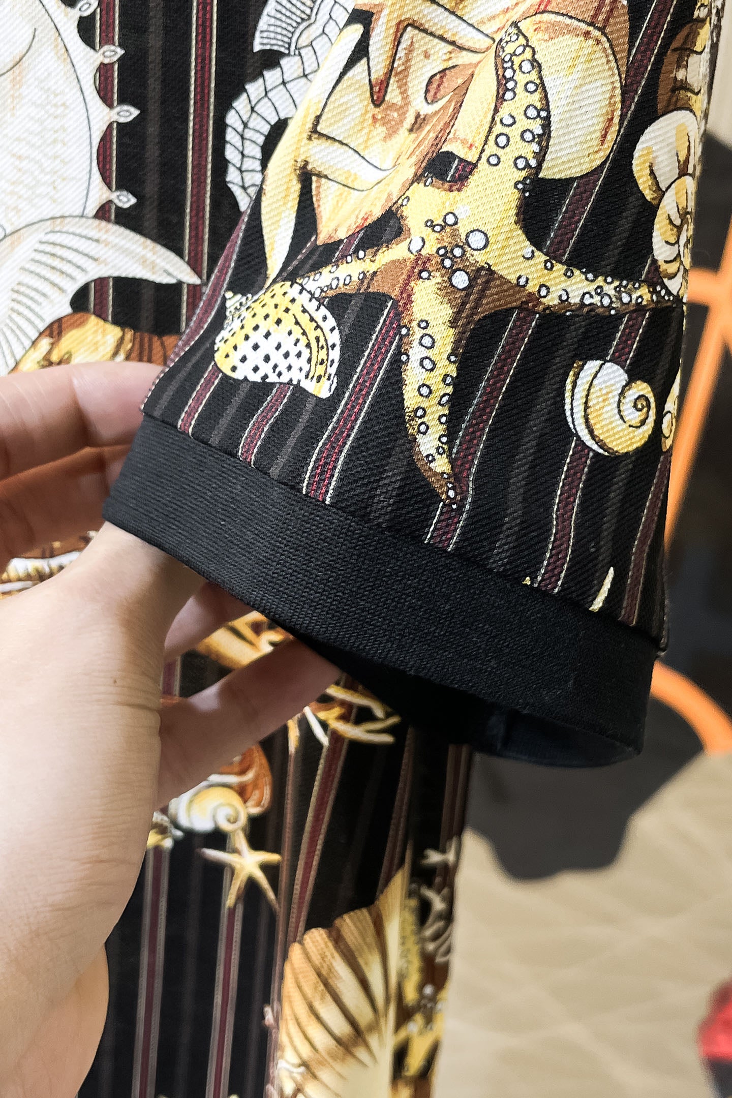 Black shirt sleeve hem with contrast trim and gold graphic pattern