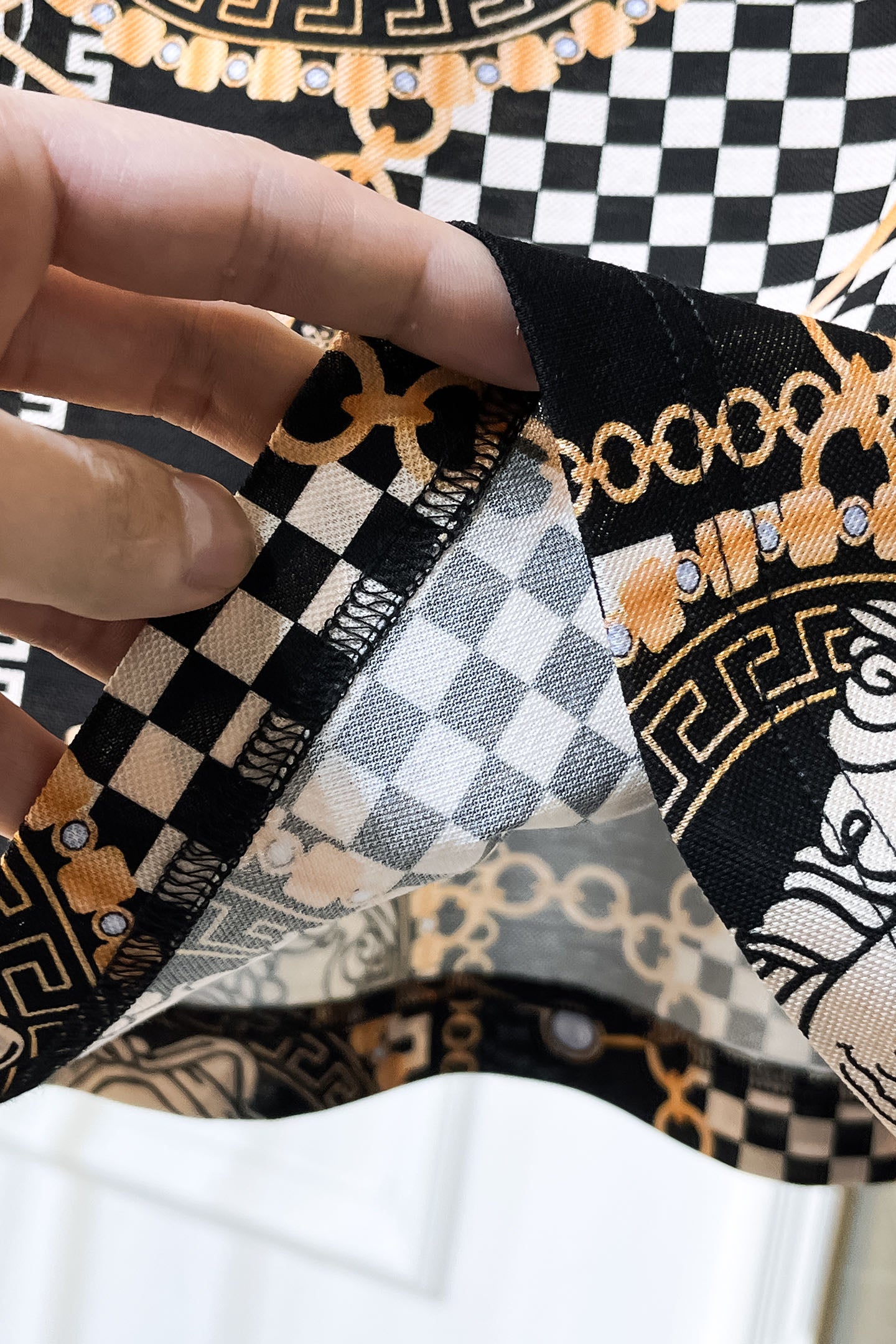 Versace shirt seam and cuff detail with black-and-white checker panel and gold chain trim