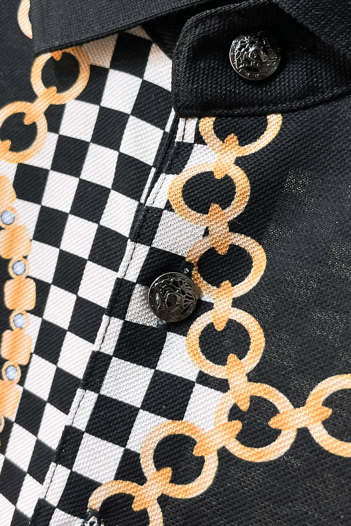 Versace shirt placket close-up with black buttons and gold chain motif on checker print
