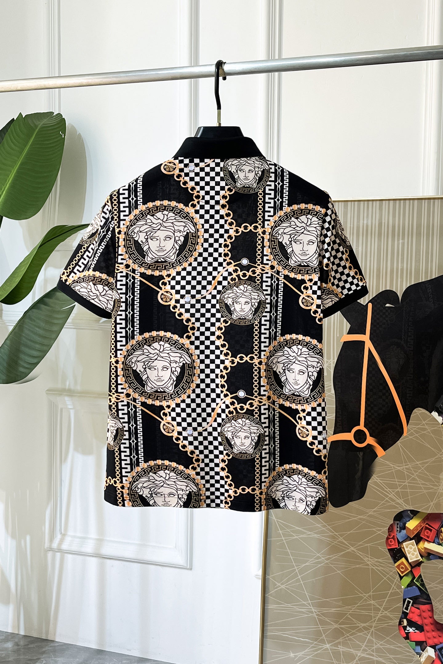 Versace short-sleeve shirt with checkerboard print, gold chain details, and Medusa-style emblems