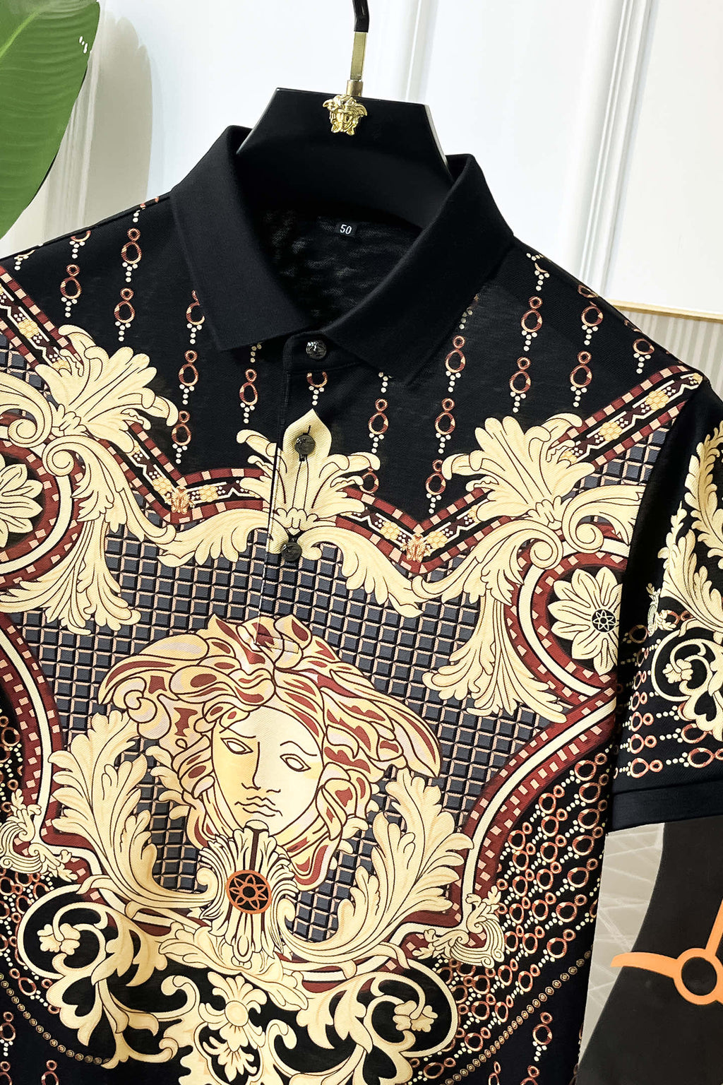 Versace polo shirt close-up of gold lion face print on black fabric