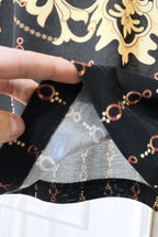 Black Versace polo shirt sleeve cuff close-up with chain motif print