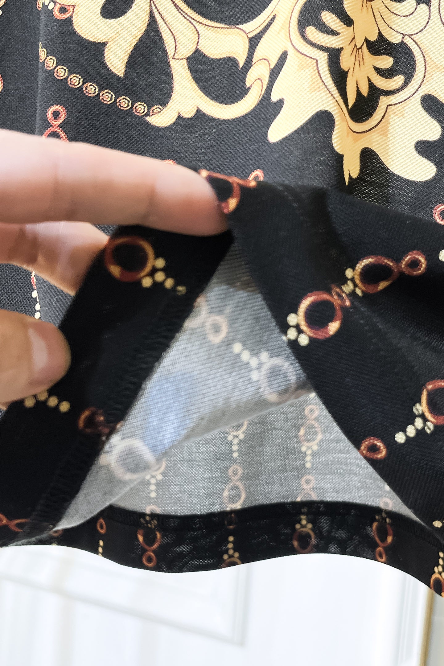 Black Versace polo shirt sleeve cuff close-up with chain motif print
