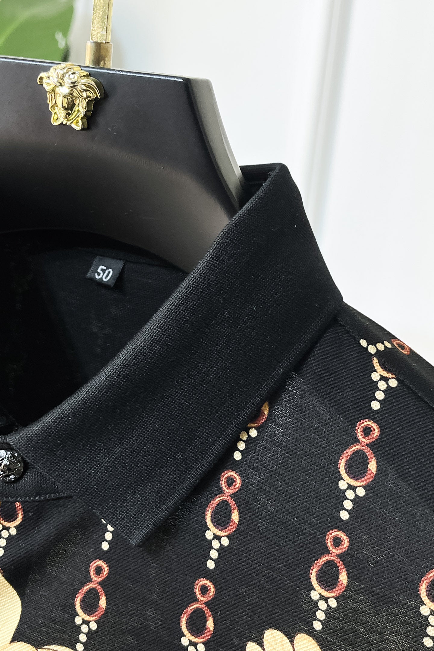 Black Versace polo neckline close-up with chain motif trim