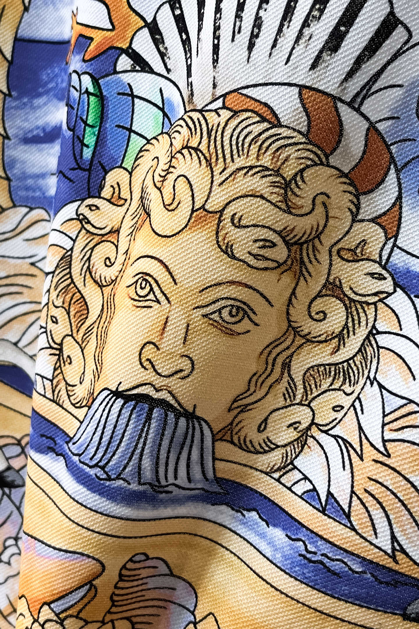 Versace polo shirt fabric detail with close-up bearded face in gold and blue tones
