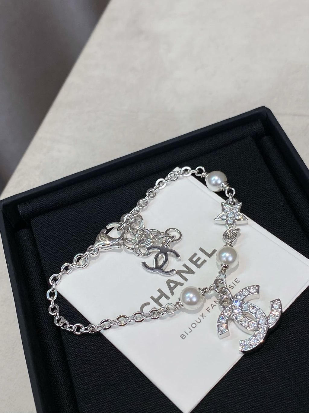 Silver charm bracelet with pearl beads and star, flower, and CC logo charms