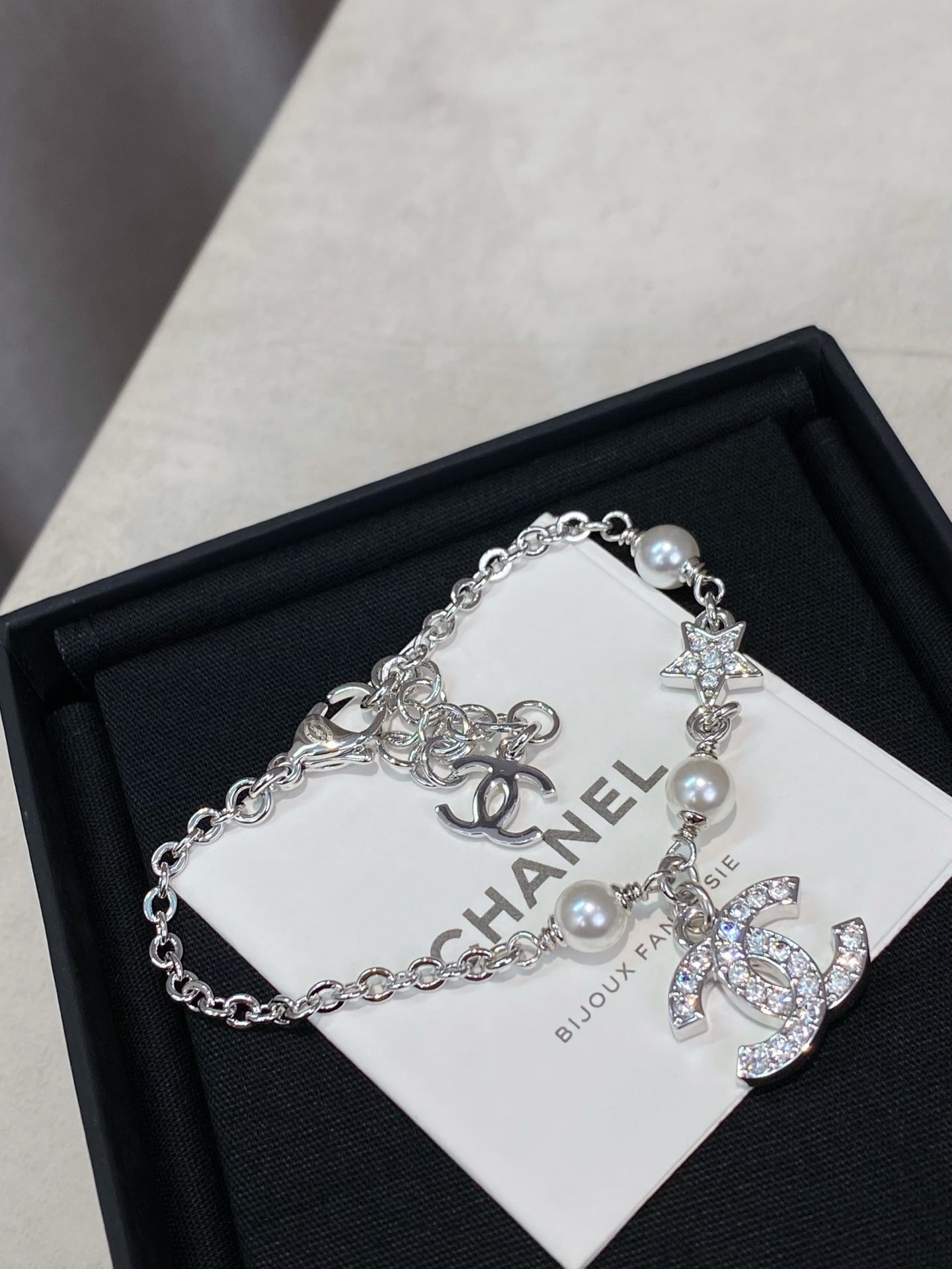 Silver charm bracelet with pearl beads and star, flower, and CC logo charms