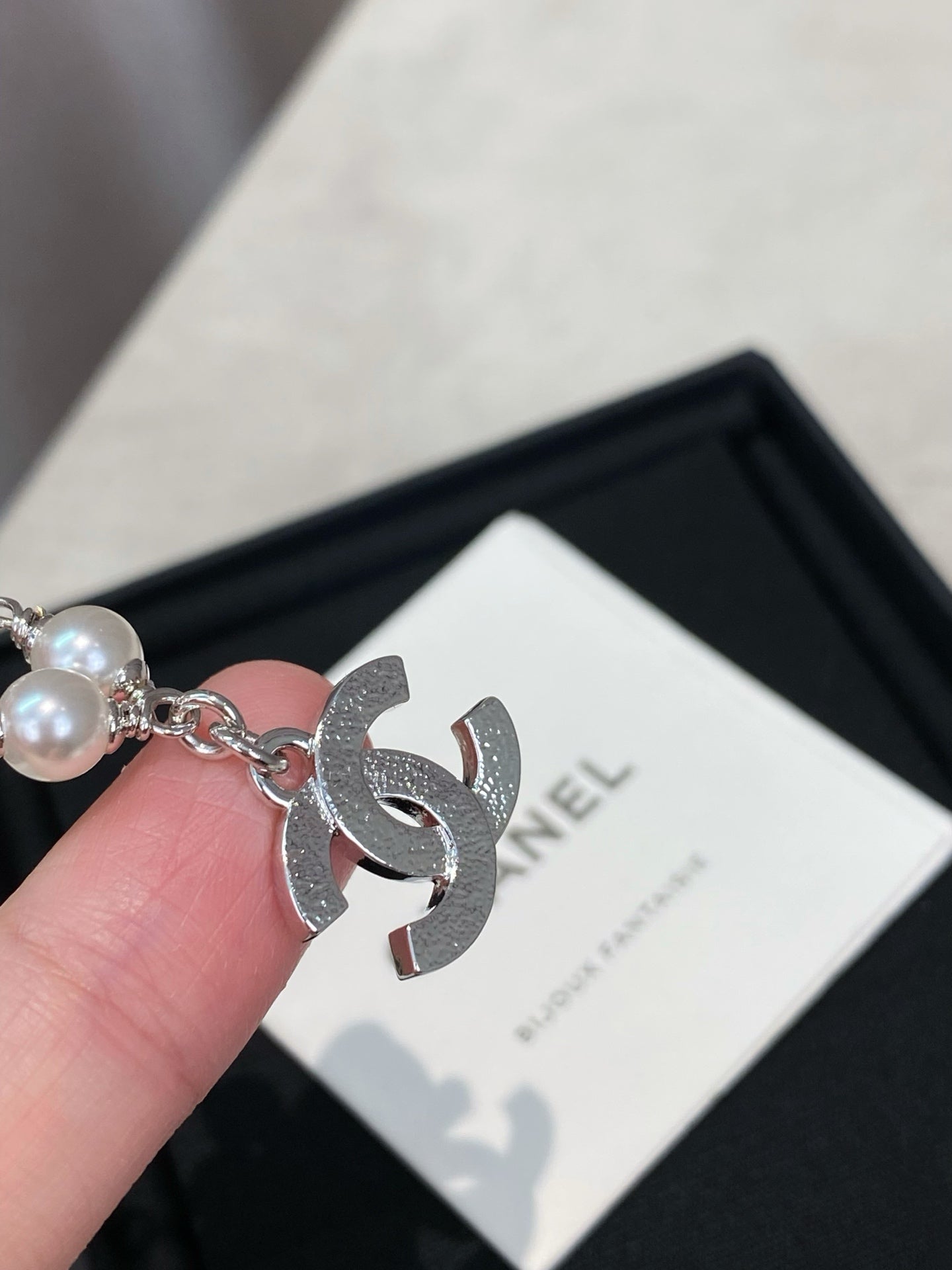 Close-up of pearl bead silver charm bracelet with large CC logo charm