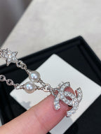 Close-up of silver charm bracelet with pearl bead and CC logo heart charm