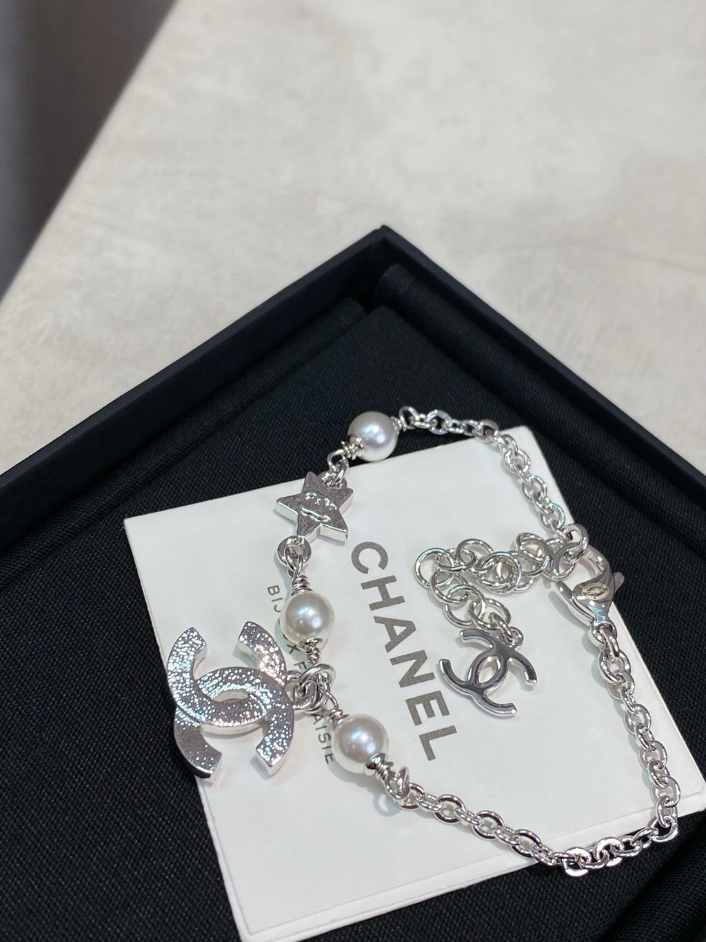 Silver charm bracelet with pearl beads and interlocking CC logo charm on card