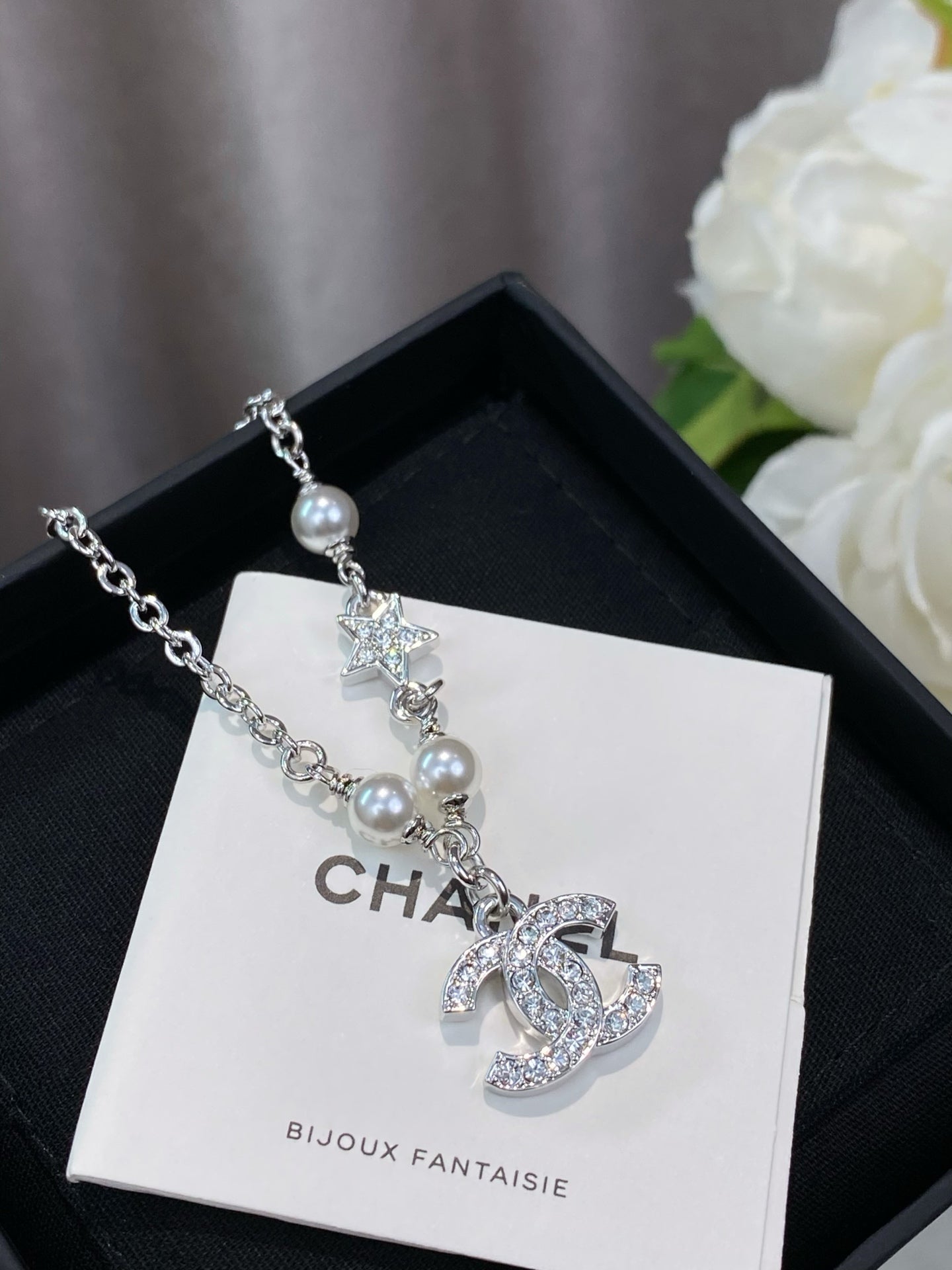 Silver charm bracelet with pearl beads, star charm, and a CC logo on card