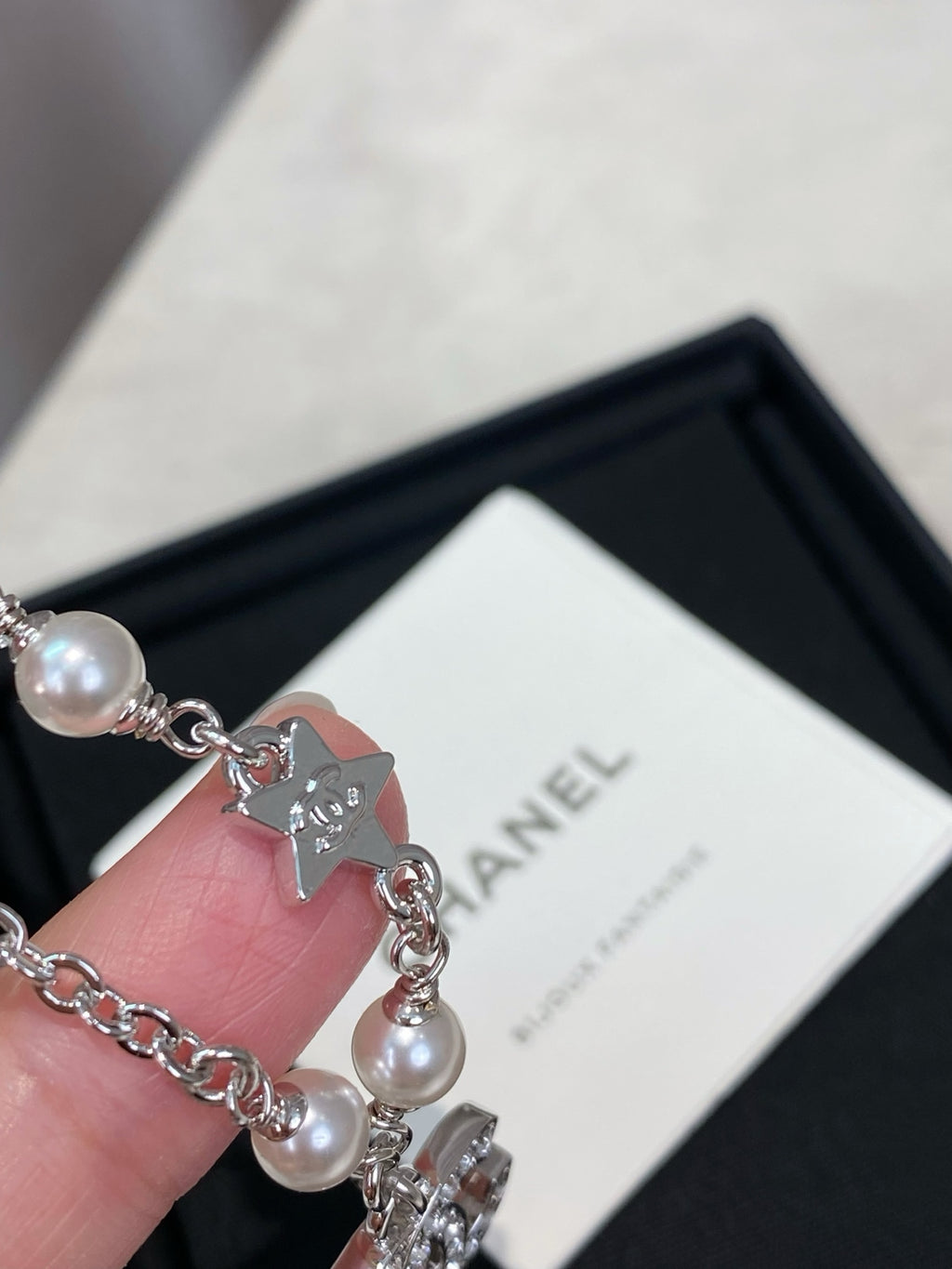 Close-up of pearl bead silver charm bracelet with cat charm pendant