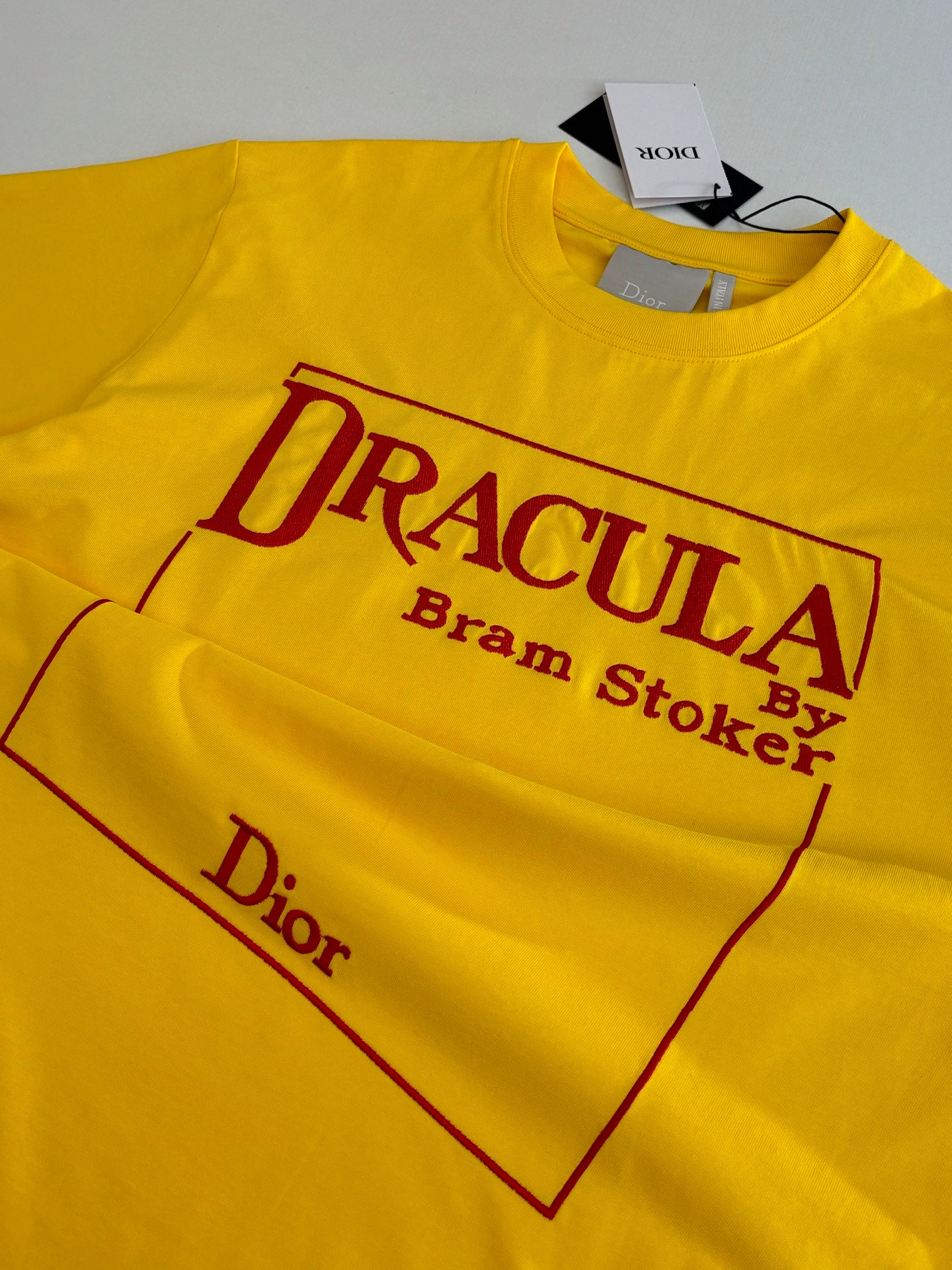 Yellow short-sleeve T-shirt detail of “DRACULA” logo graphic and “Dior” text.