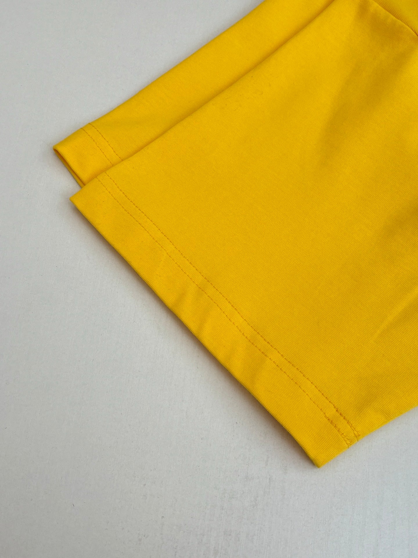 Yellow short-sleeve T-shirt sleeve and hem edge with visible stitching.