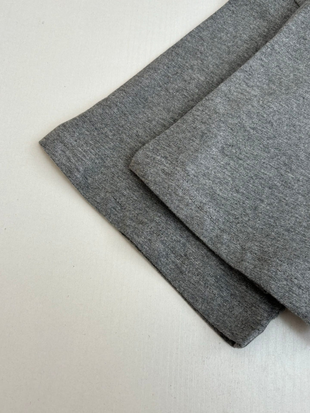 Gray T-shirt fabric folds showing sleeve length and smooth knit texture