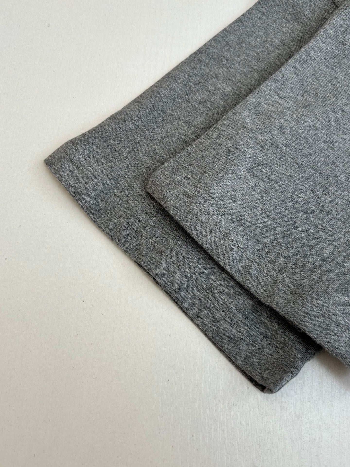 Gray T-shirt fabric folds showing sleeve length and smooth knit texture
