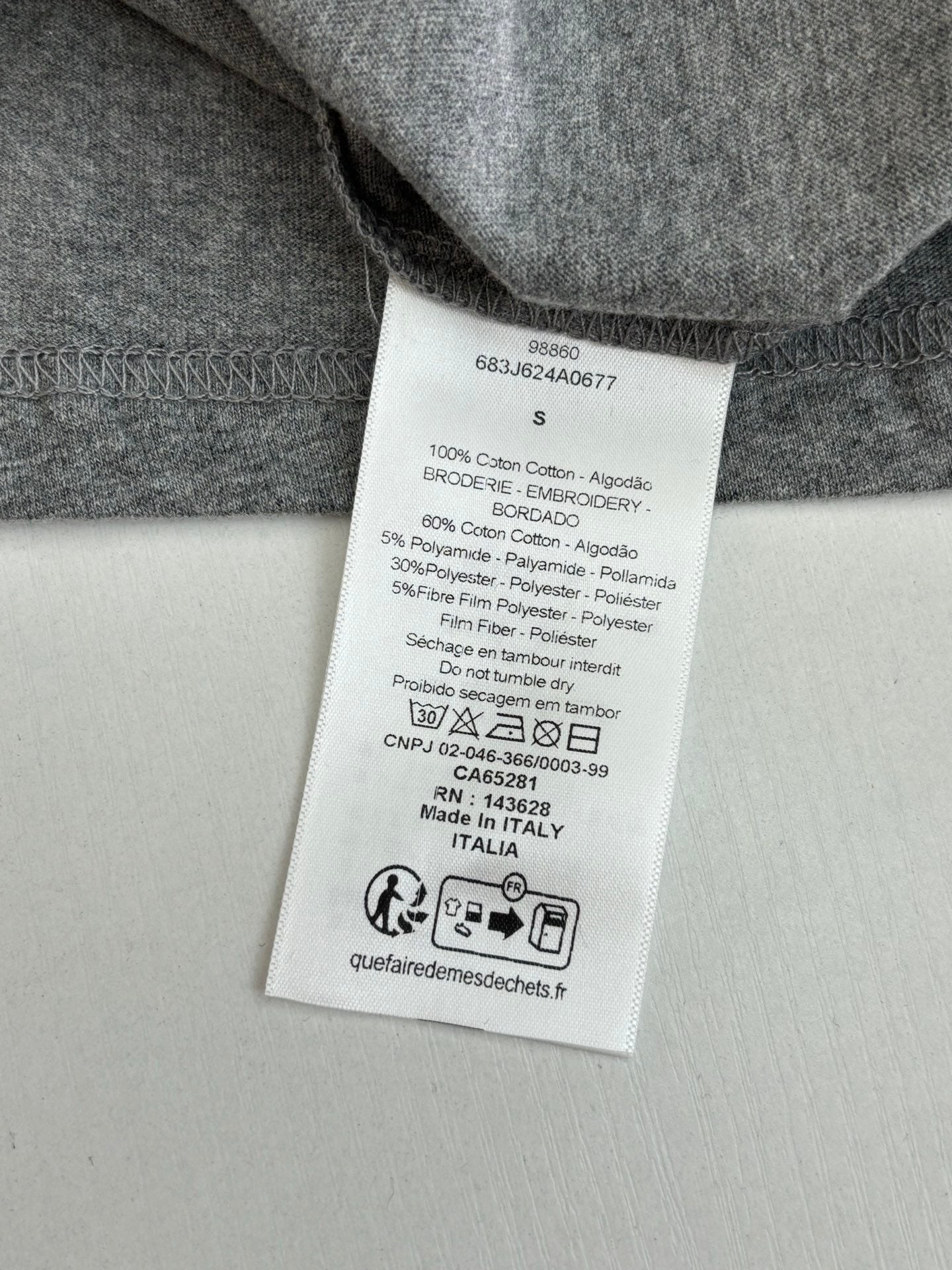 Gray T-shirt care label on inside neck with size and composition text