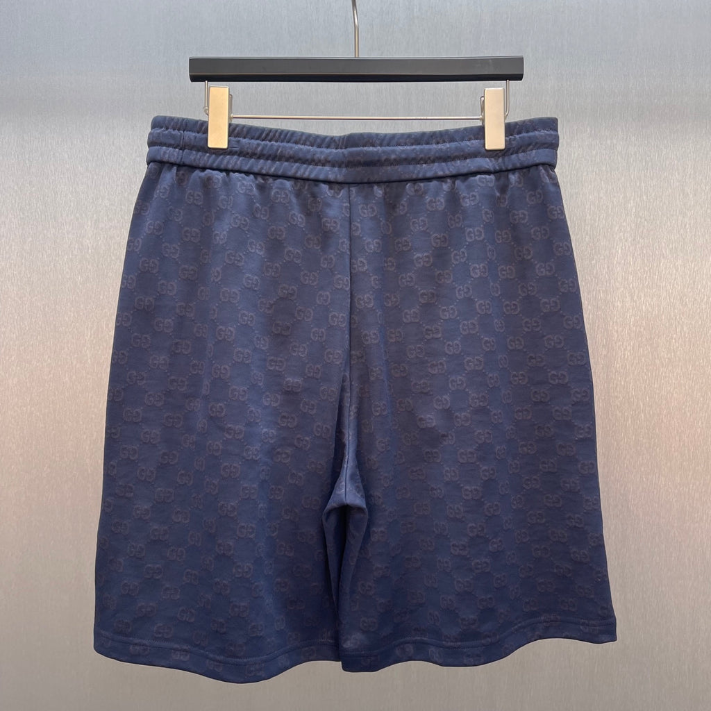 Gucci shorts front view, dark blue with GG logo pattern and elastic waistband