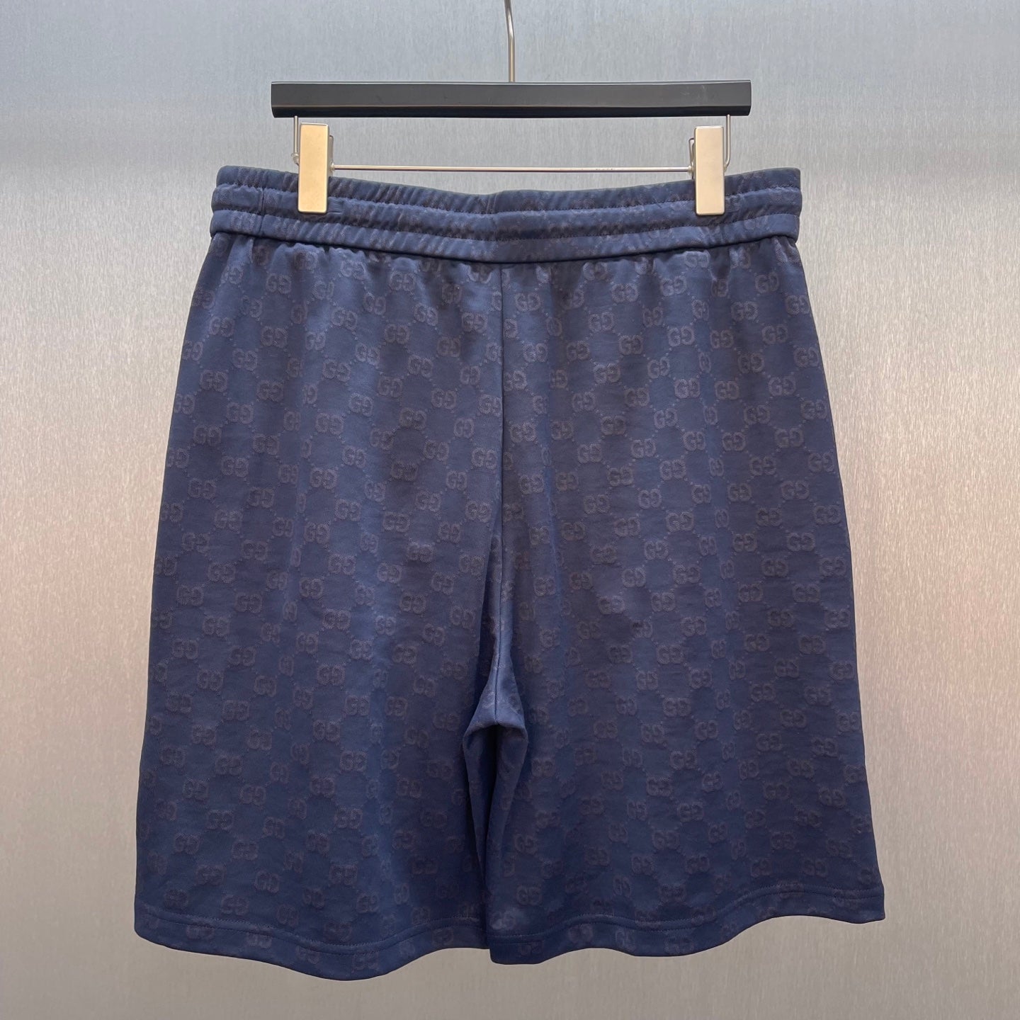 Gucci shorts front view, dark blue with GG logo pattern and elastic waistband